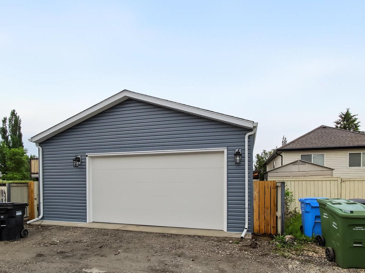 Finished garage in Evergreen in blue vinyl siding with a white overhead door set off centre
