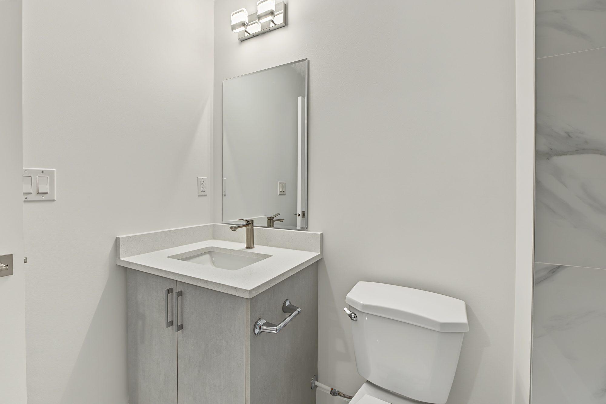 Custom vanity with quartz top, rectangular sink, chrome faucet and mirror