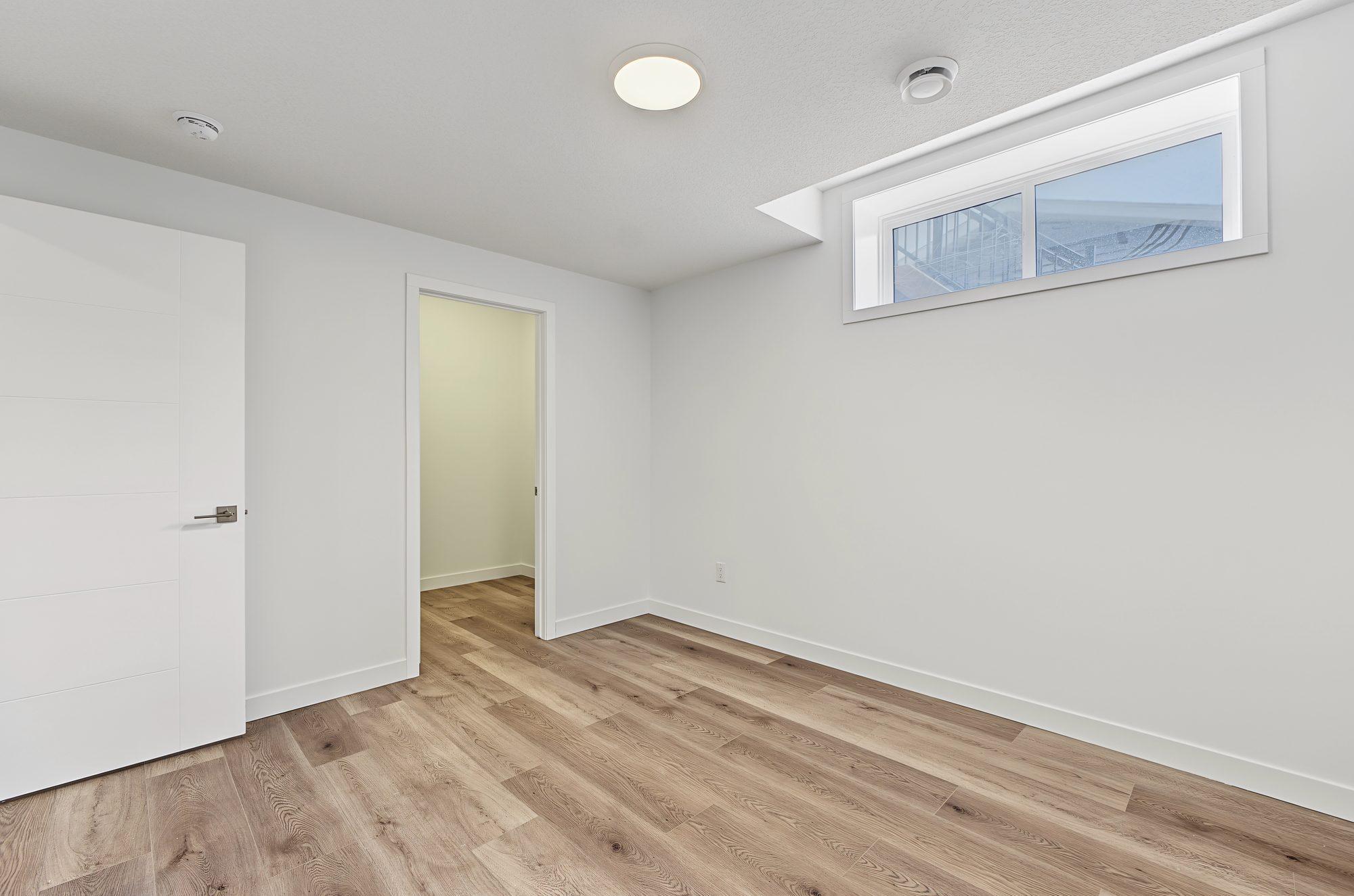 Suite bedroom with an egress window, a pot light, and doors to the walk-in closet and the hall