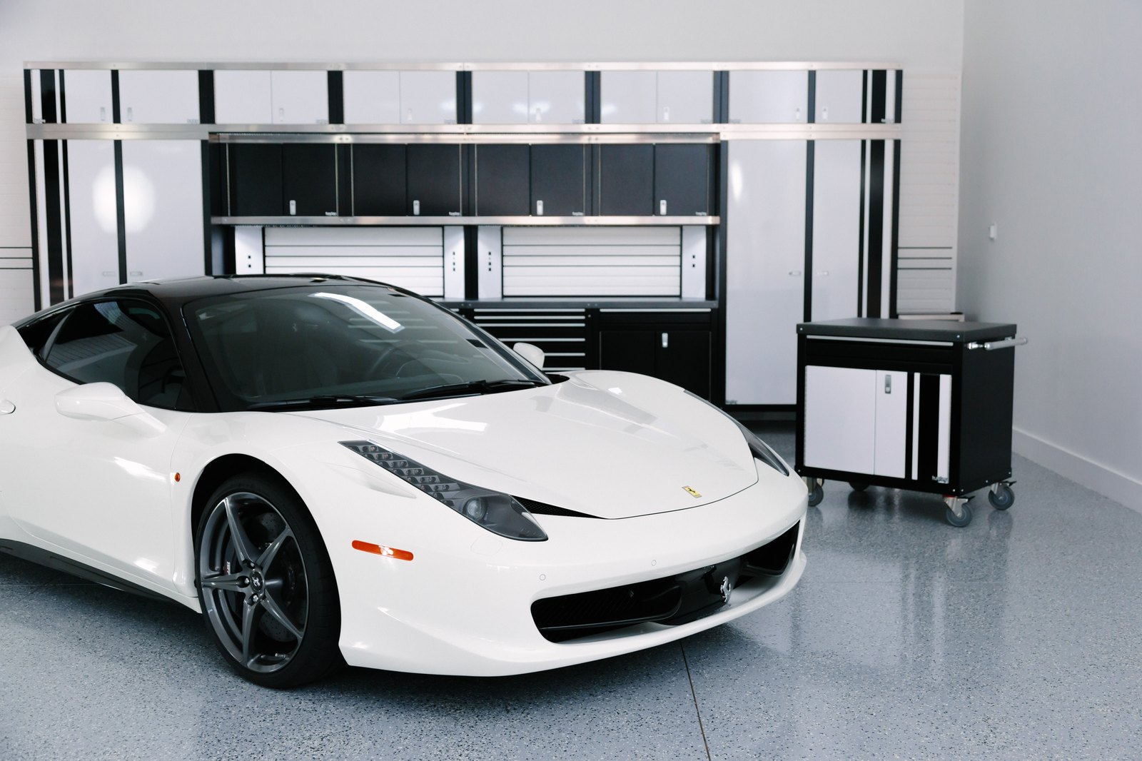 White-doored Cabinets by Hayley wall with closets, uppers and tool chests behind a white sports car