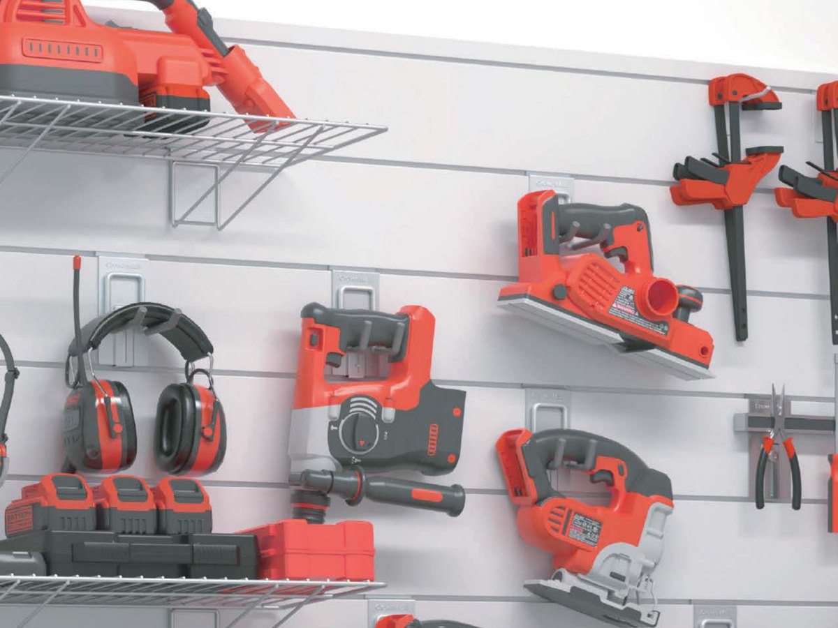 Power tools, ear defenders and clamps hanging on slatwall hooks, with a wire shelf above